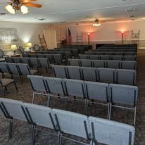 Empty church sanctuary with rows of gray chairs facing a podium and American flag at the front