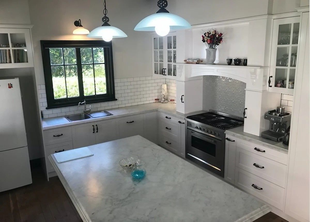A Kitchen with White Cabinets and A Large Island in The Middle — Sheridan Stone Aust in Toormina, NSW