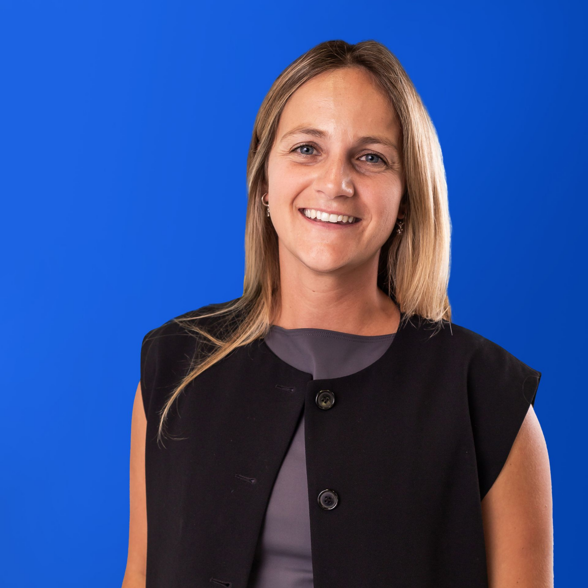 A woman in a black and white polka dot shirt is smiling in a yellow circle.