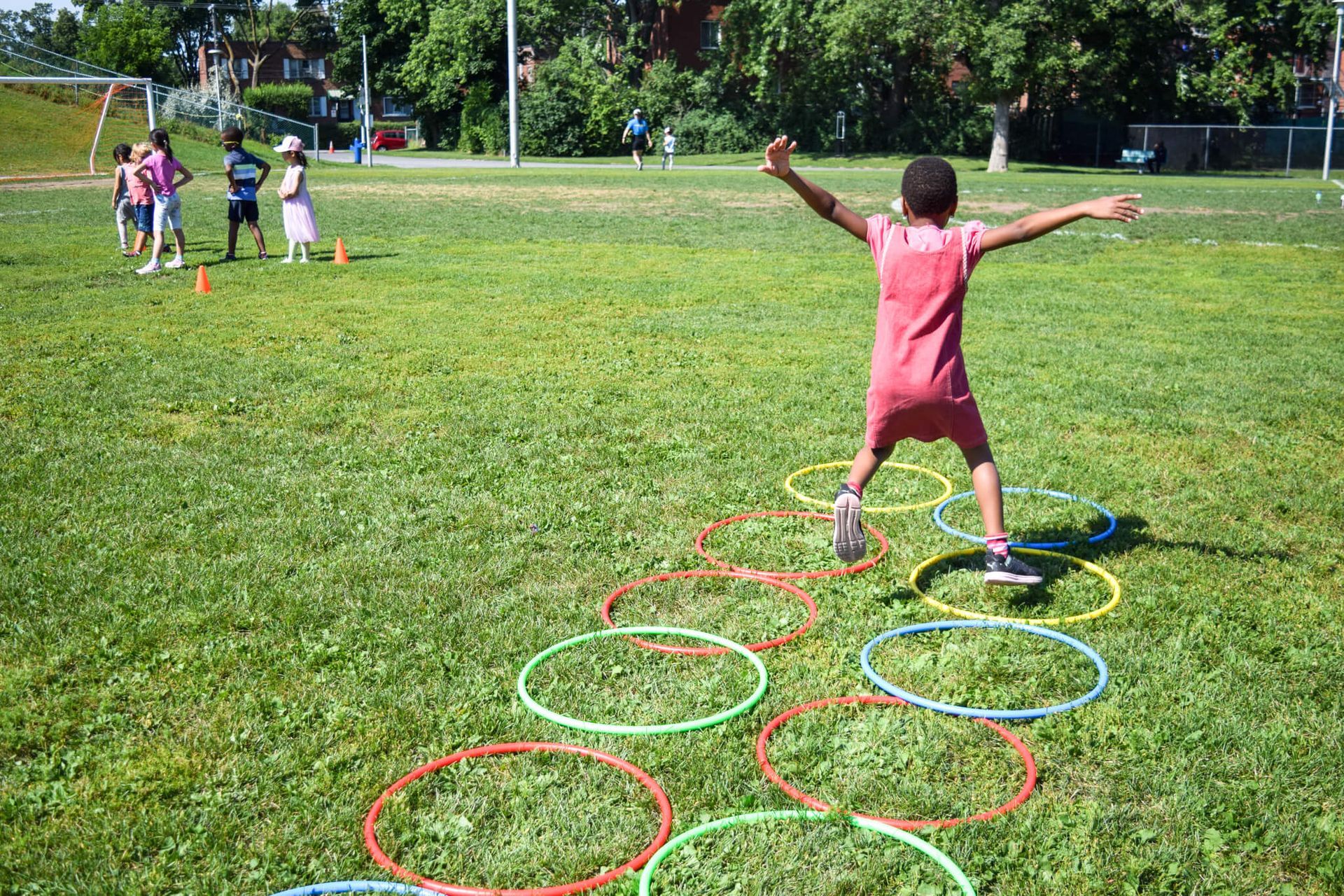 A young girl is jumping through hula hoops in a field.