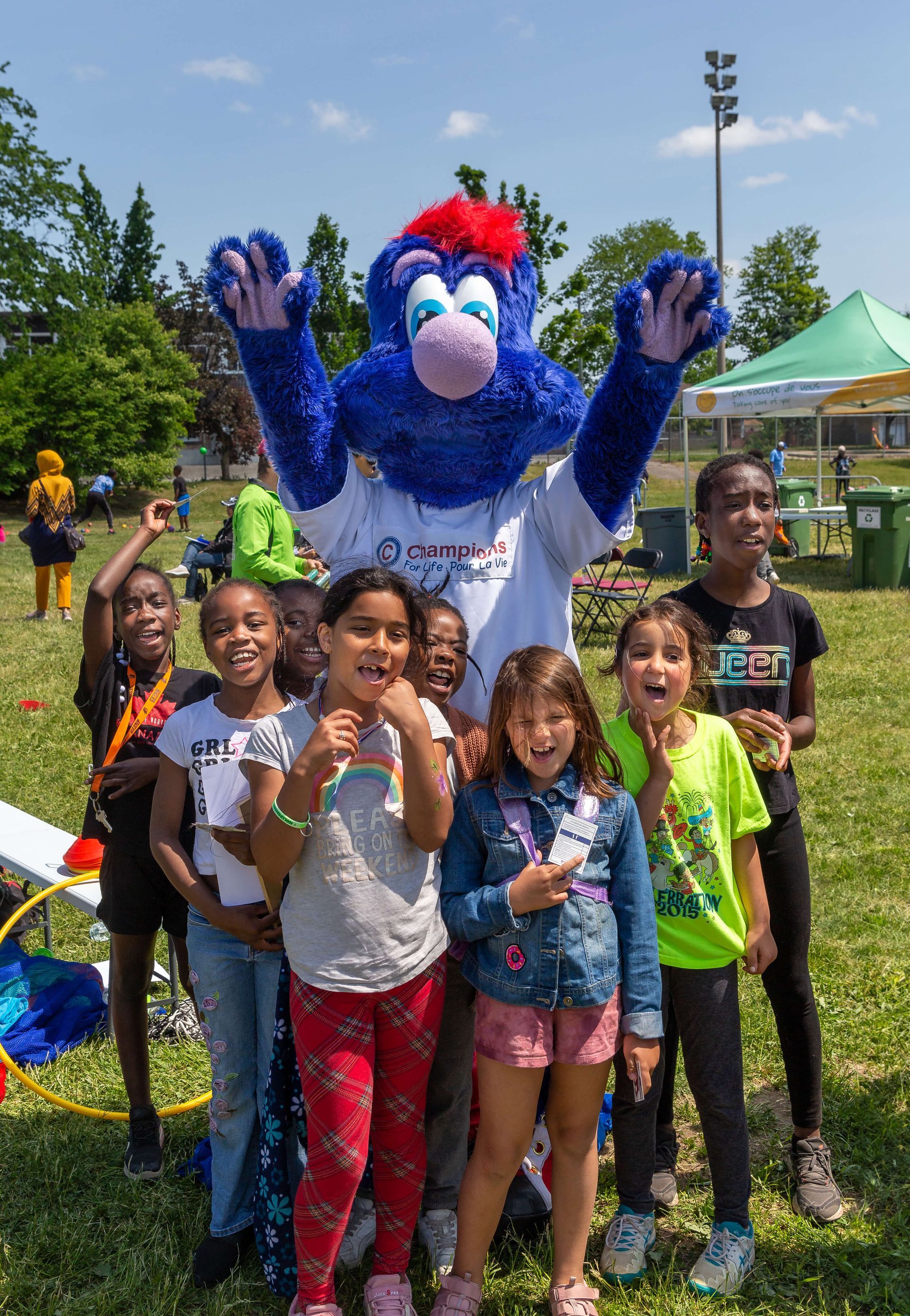 A group of children are posing for a picture with a blue mascot.