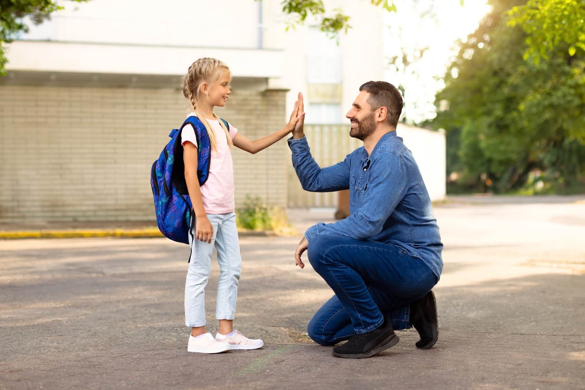 A man and a little girl are giving each other a high five.