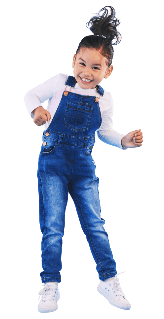 A little girl in overalls is dancing and smiling.