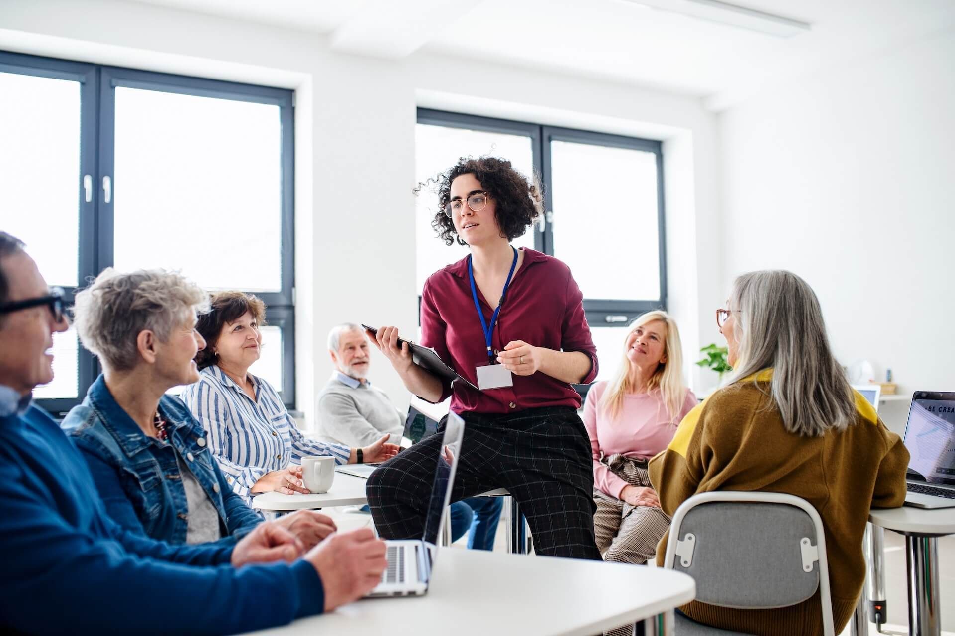A woman is giving a presentation to a group of people sitting at tables.