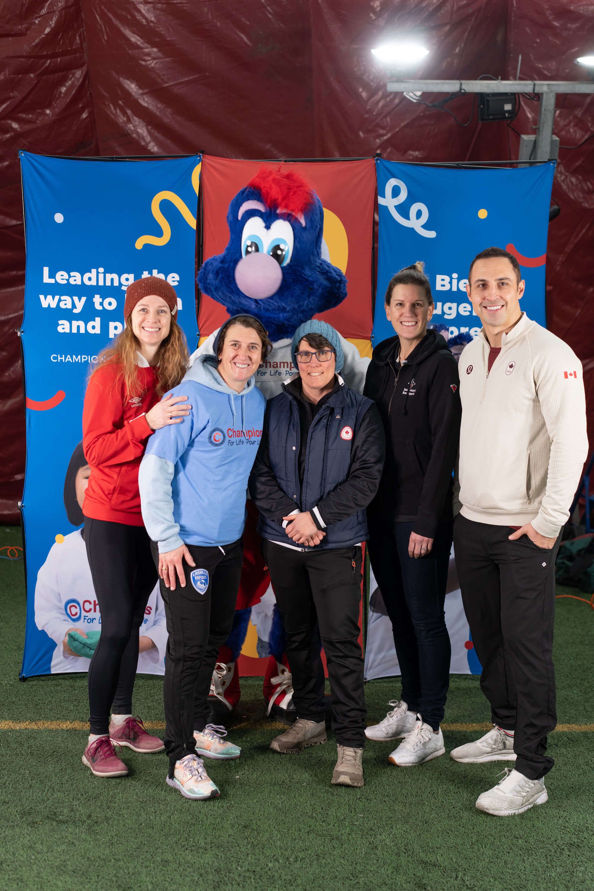 A group of people are posing for a picture in front of a mascot.