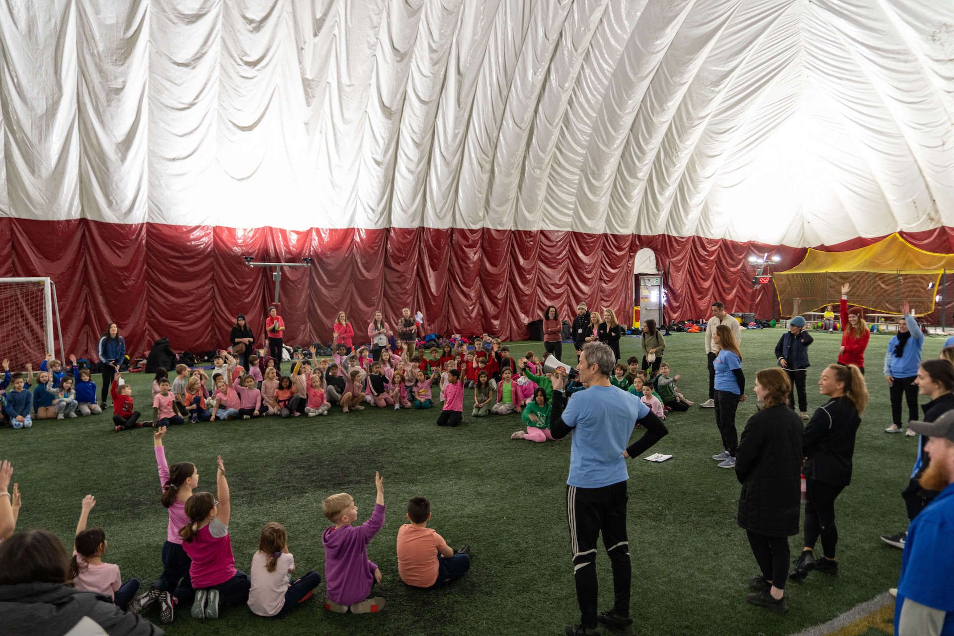 A group of people are sitting on the grass in an indoor stadium.