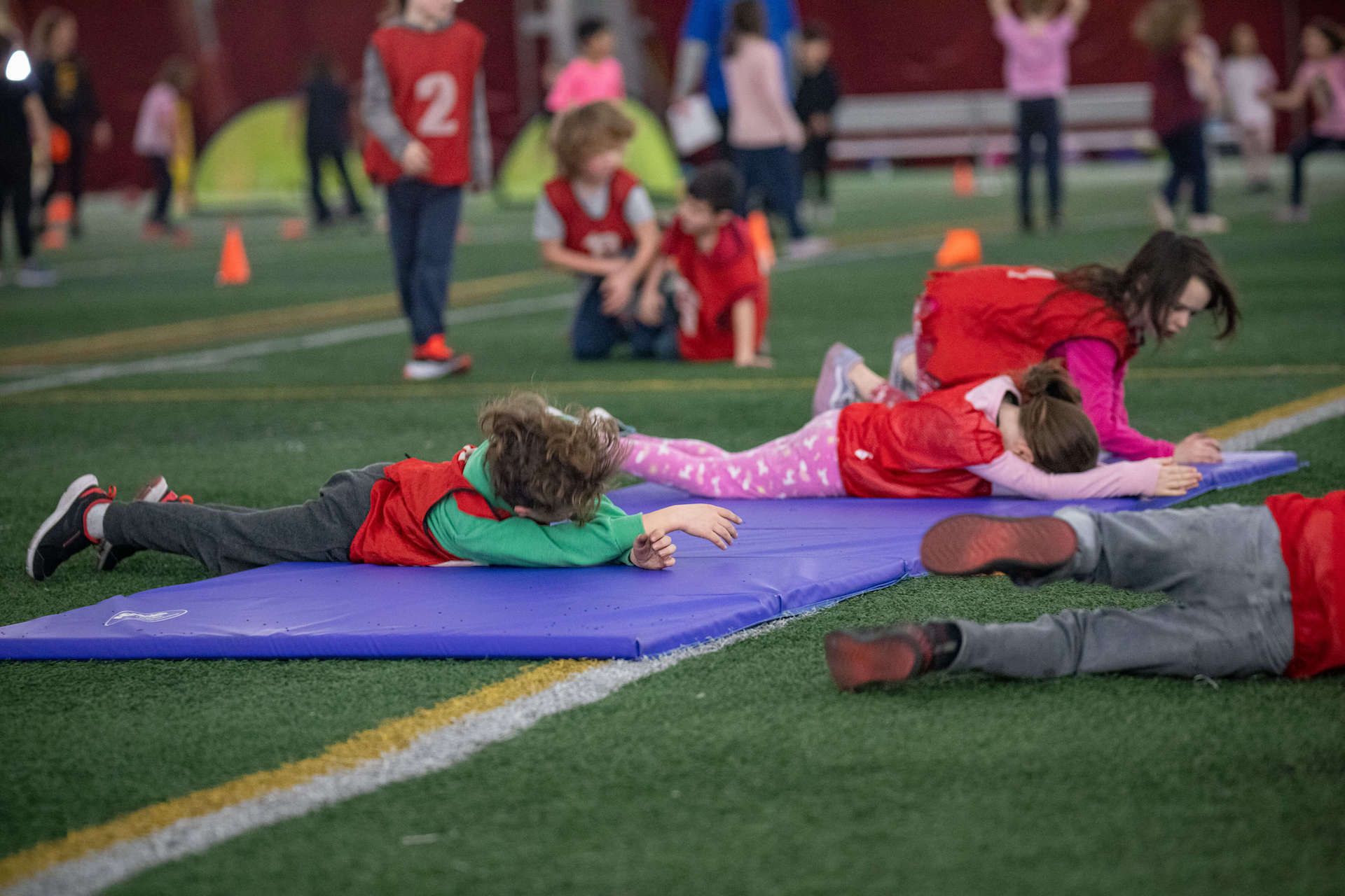 A group of children are laying on mats on a field.