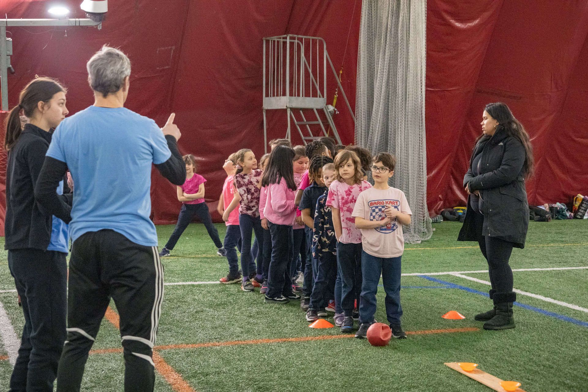 A group of children are standing in a line on a soccer field.