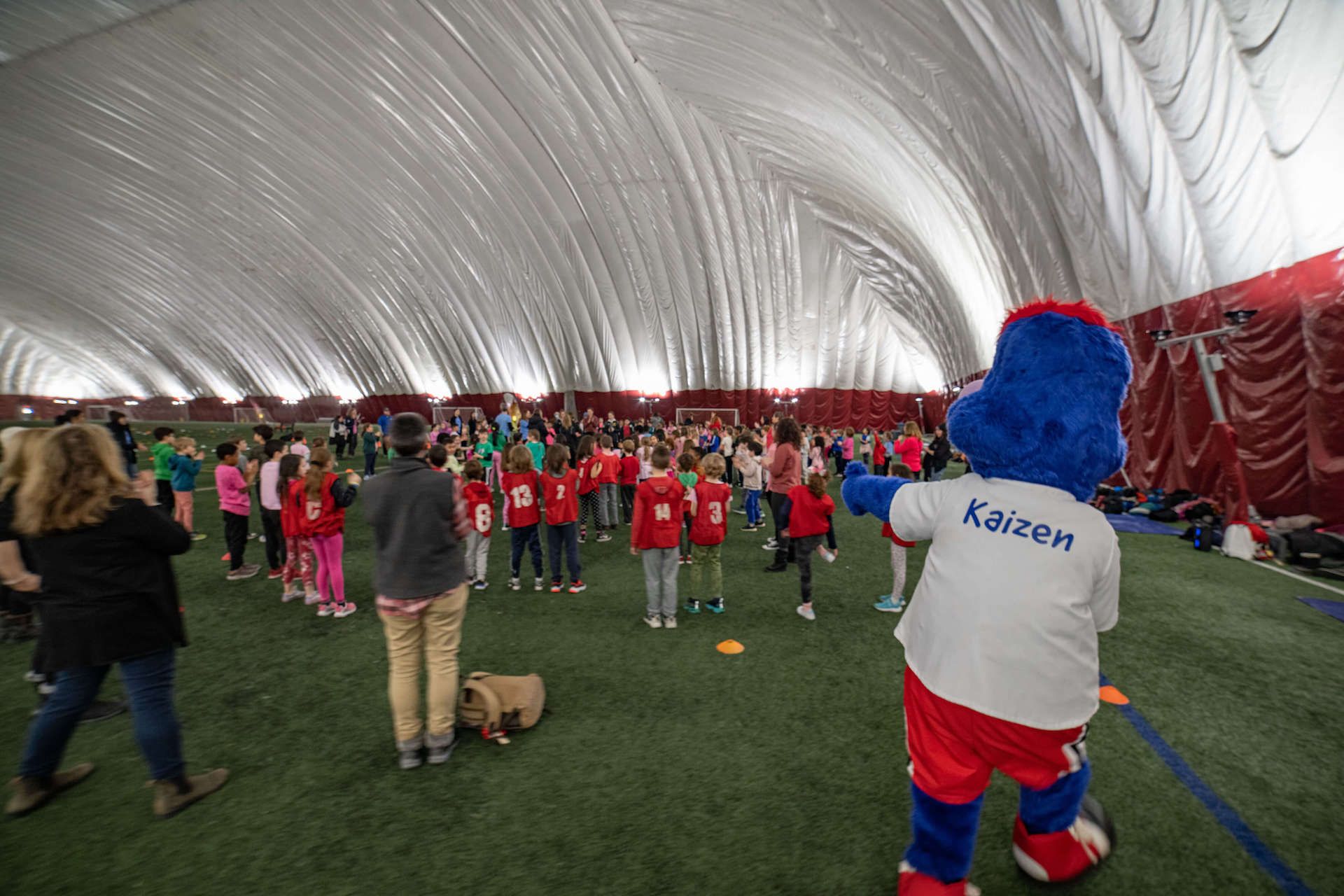 A mascot is standing in front of a group of children.