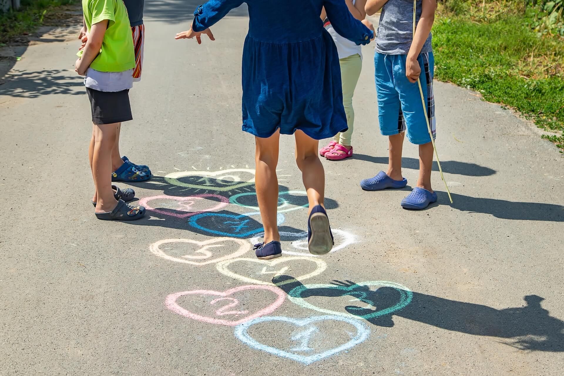 A group of children are playing hopscotch on the side of a road.