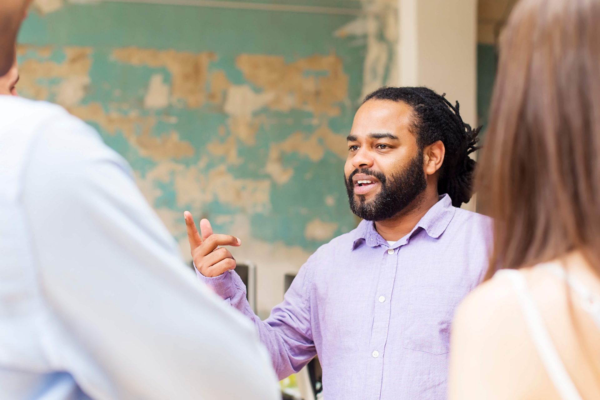 A man in a purple shirt is talking to a group of people.