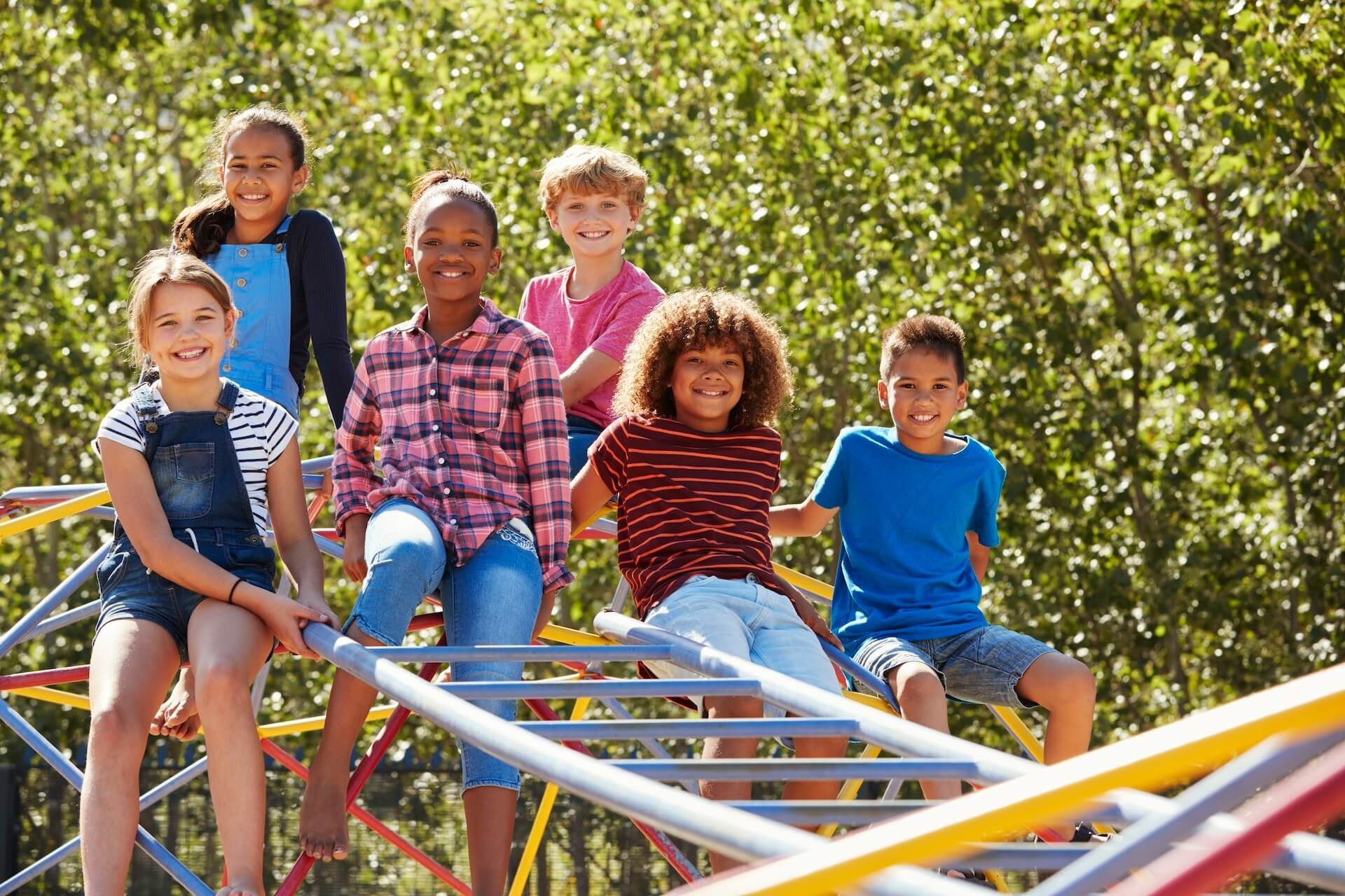 A group of children are sitting on a monkey bars at a playground.