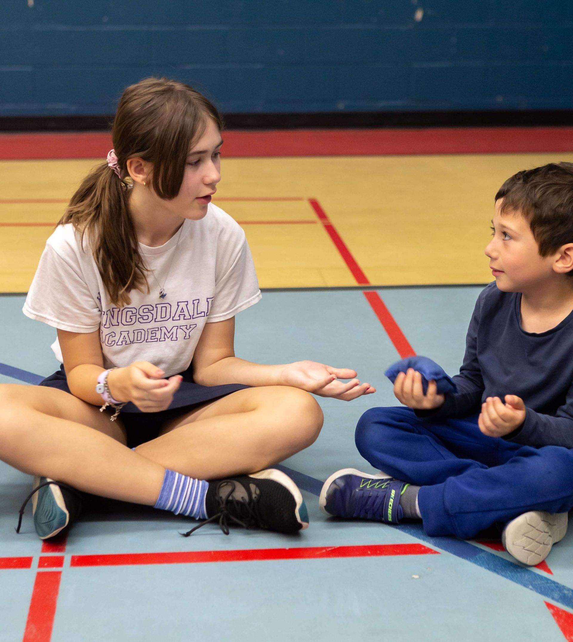 A girl and a boy are sitting on the floor talking