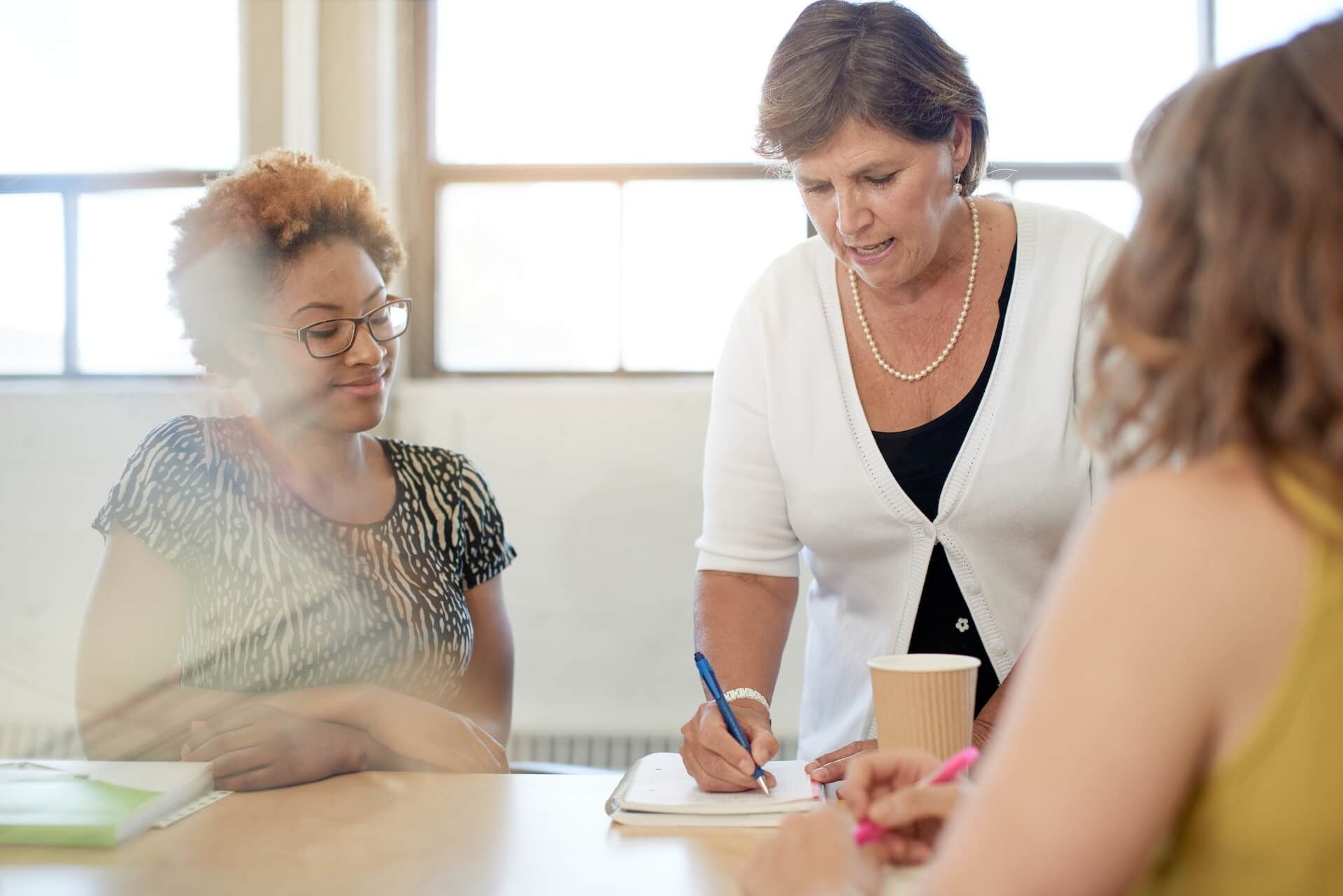 A group of women are sitting at a table having a meeting.