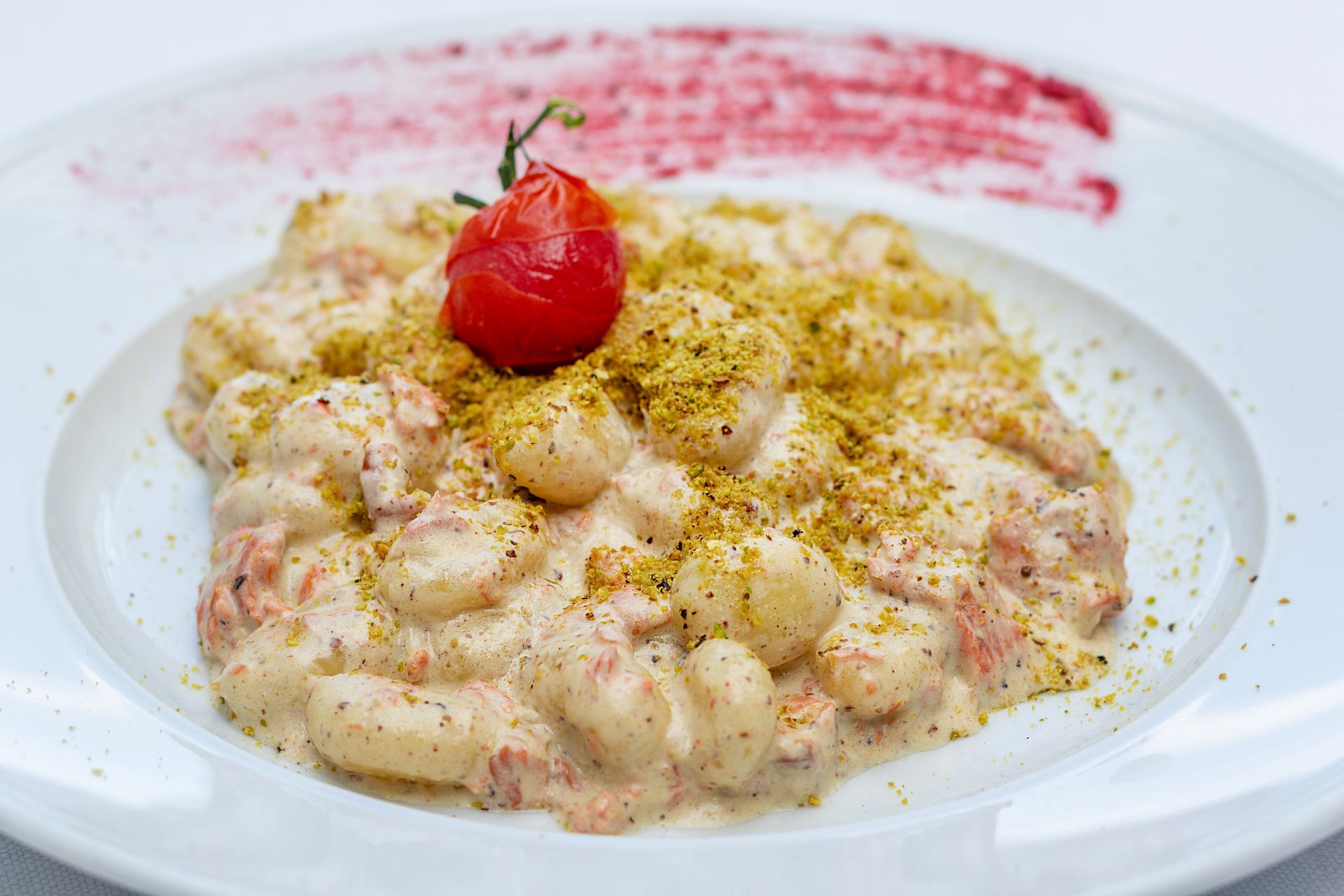 Gnocchi in salsa cremosa, conditi con pomodoro e condimenti, su un piatto bianco.