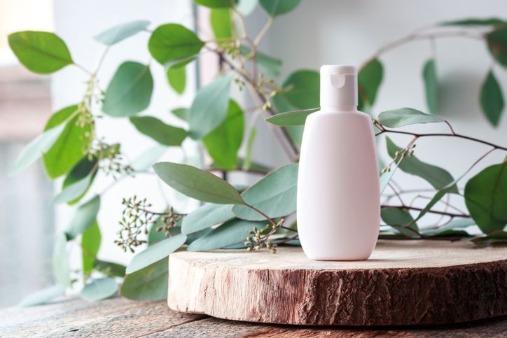 Cosmetic bottle with green leaves of eucalyptus