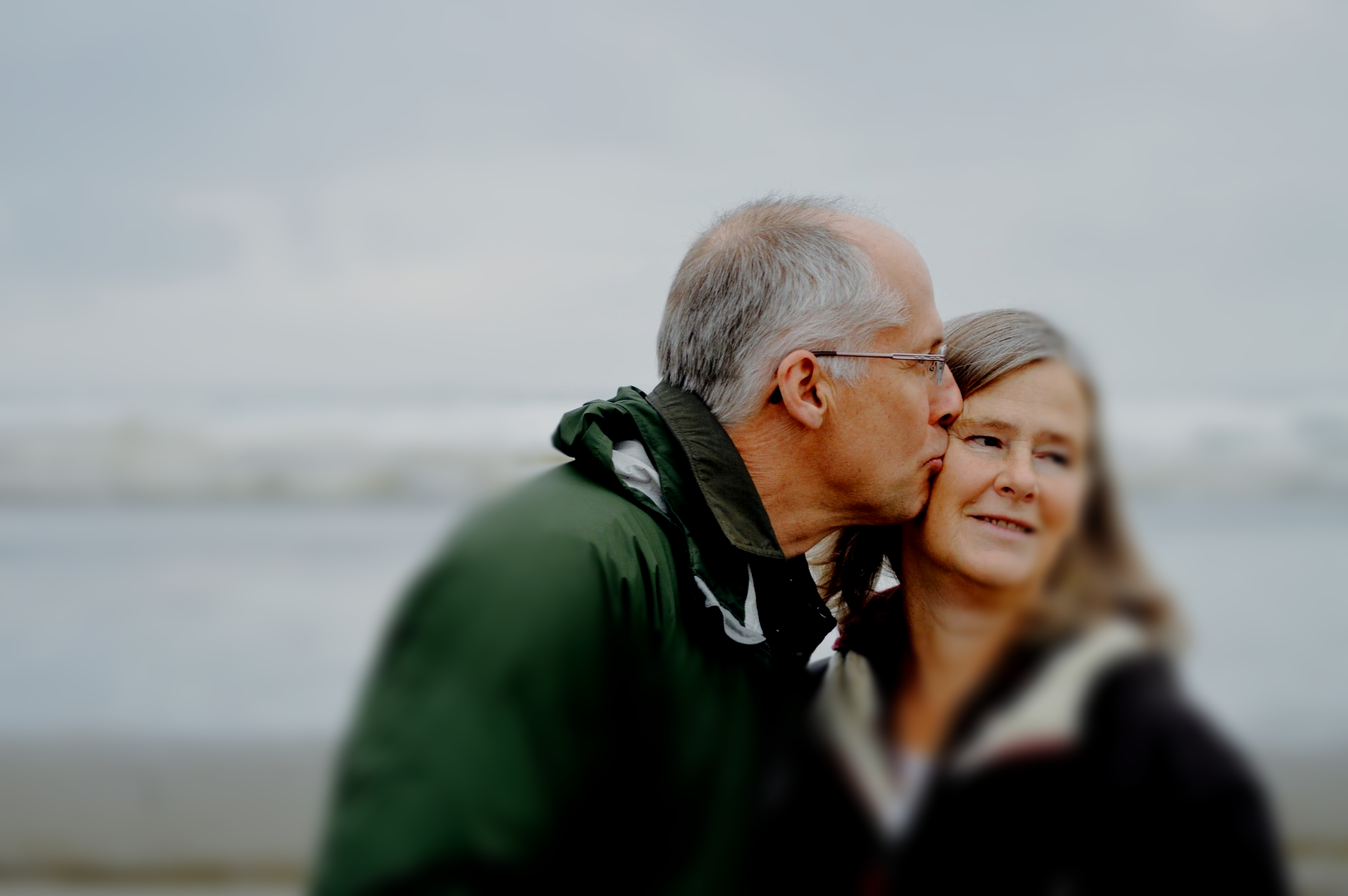 A man is kissing a woman on the cheek on a beach