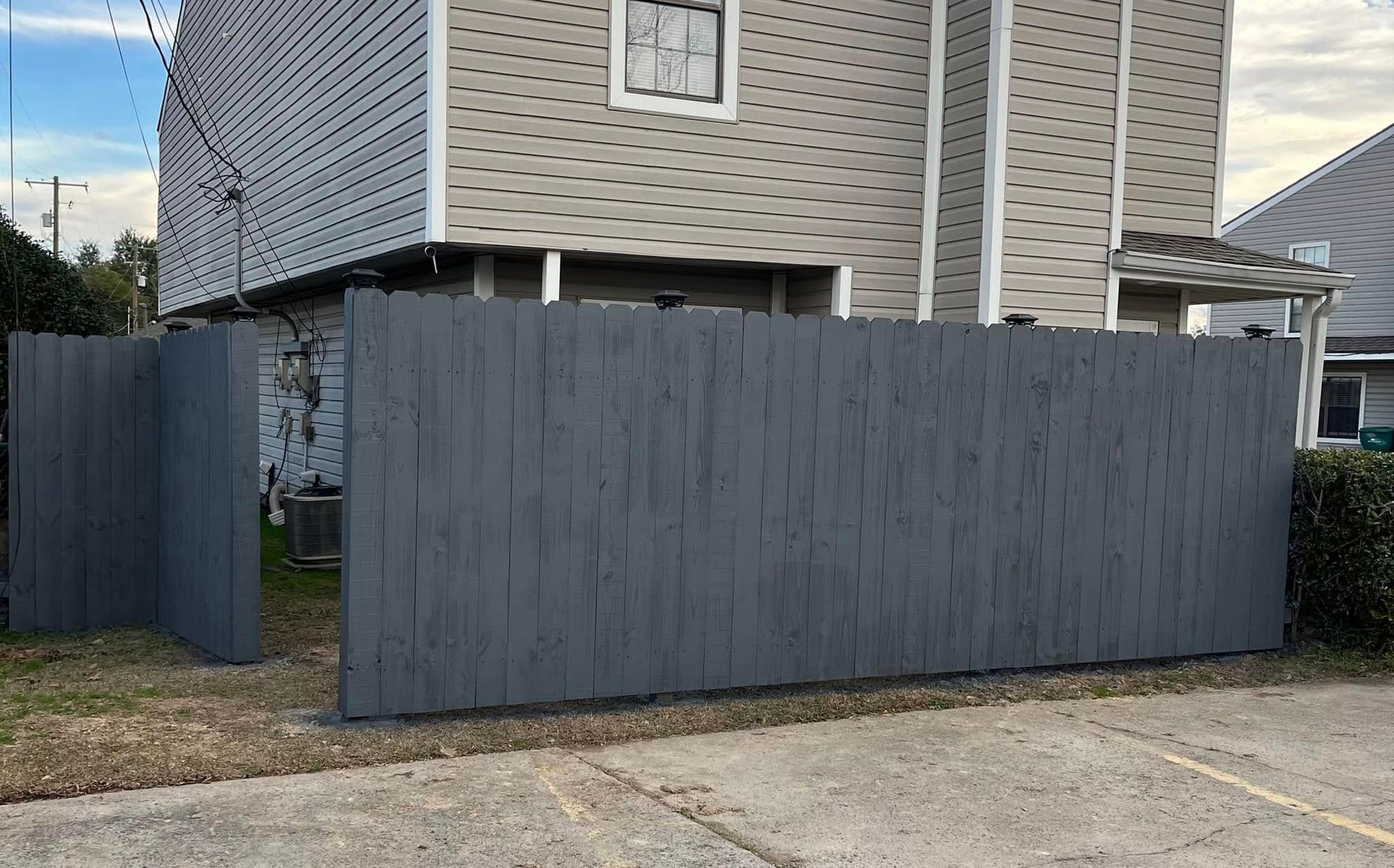 A gray wooden fence surrounds the base of a two-story building.