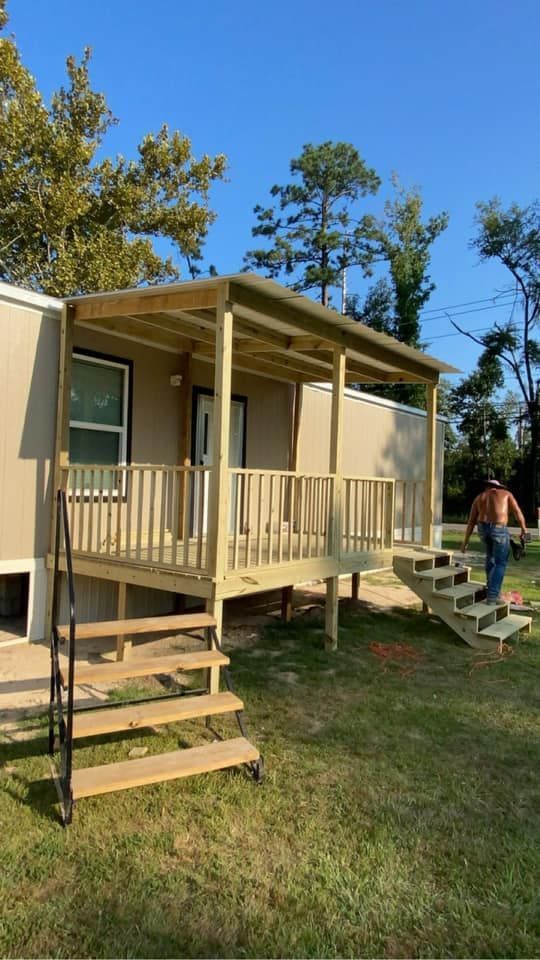 Wooden deck with roof attached to a beige building. A person walks up outdoor steps on the right.