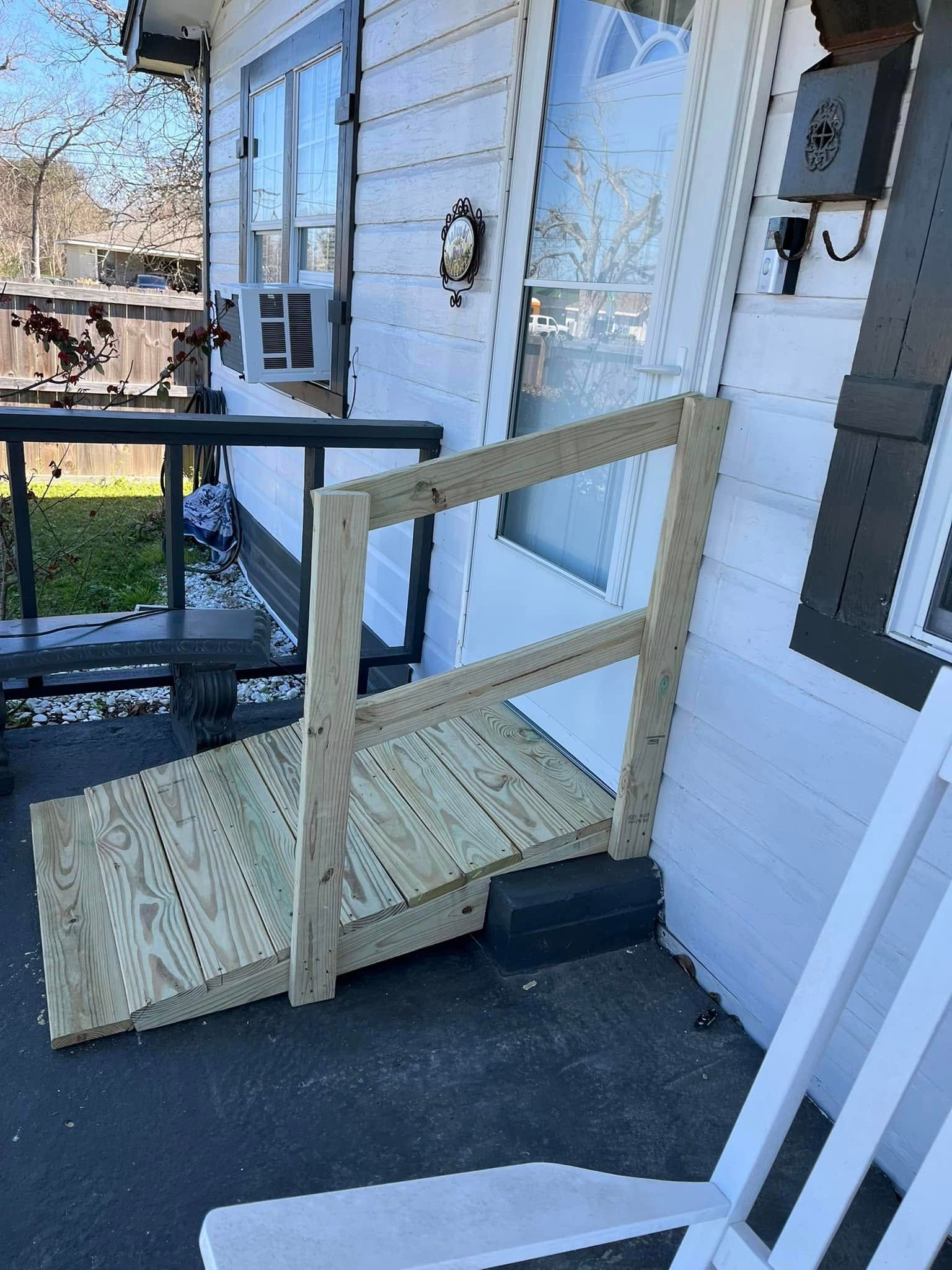 Wooden ramp with handrail leading to a white house door.