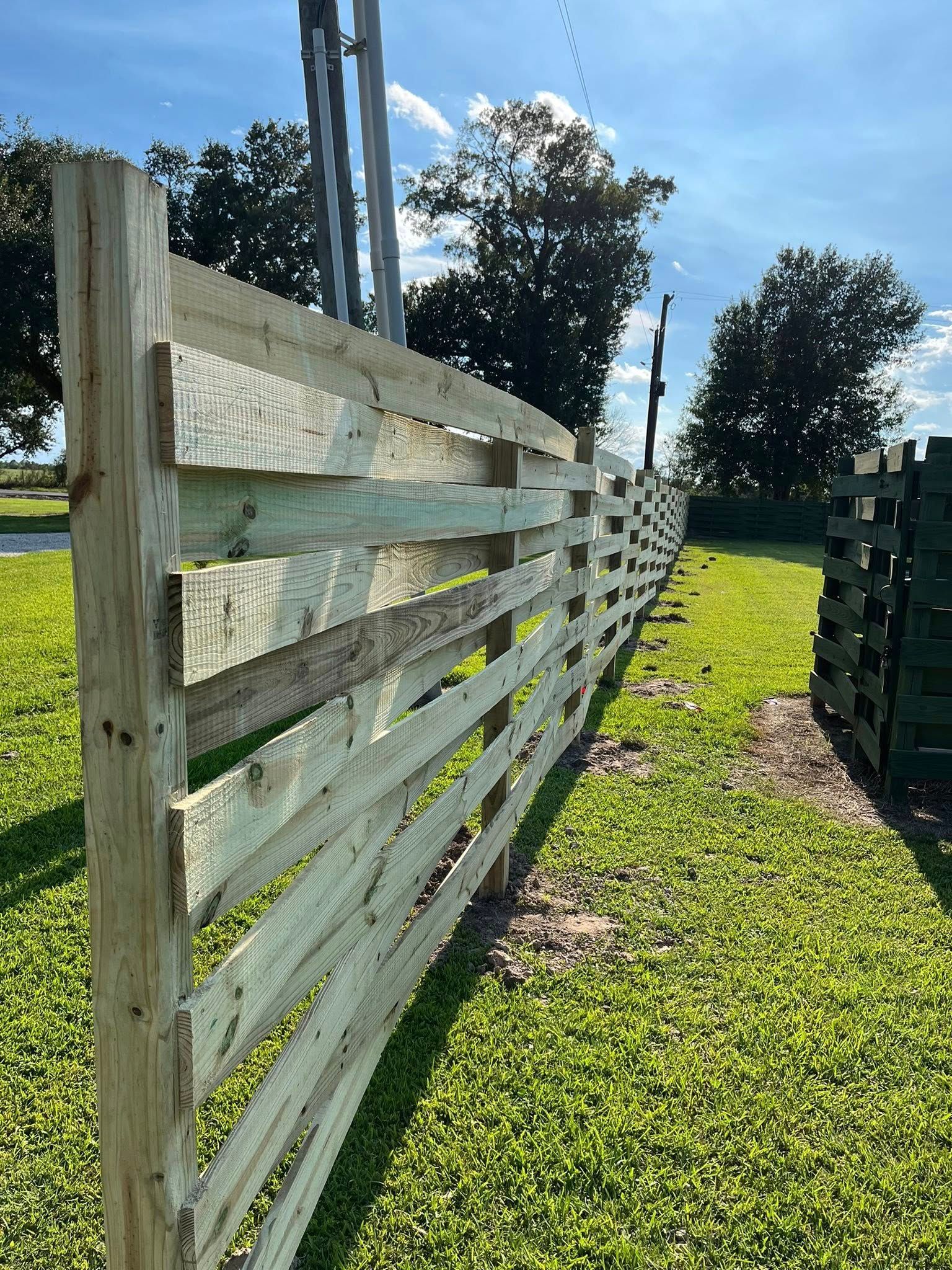 Wooden fence in a grassy area, with a telephone pole in the background.