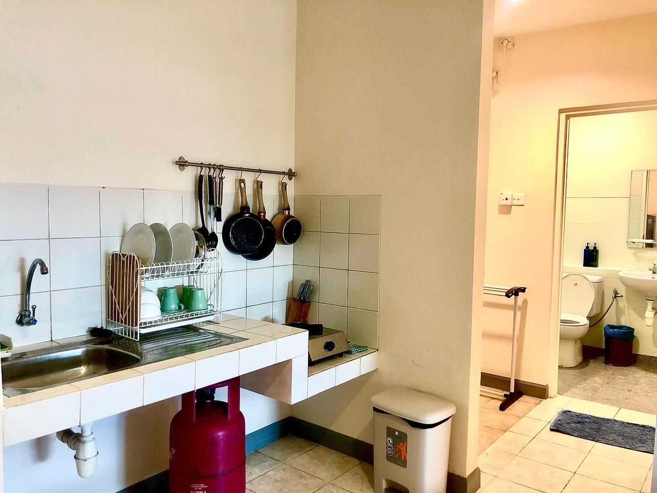 The kitchen includes appliances such as a refrigerator, stove, frying pan, boiling pan, and sink. There is also a dining area with a table and chairs, then simple cutleries.