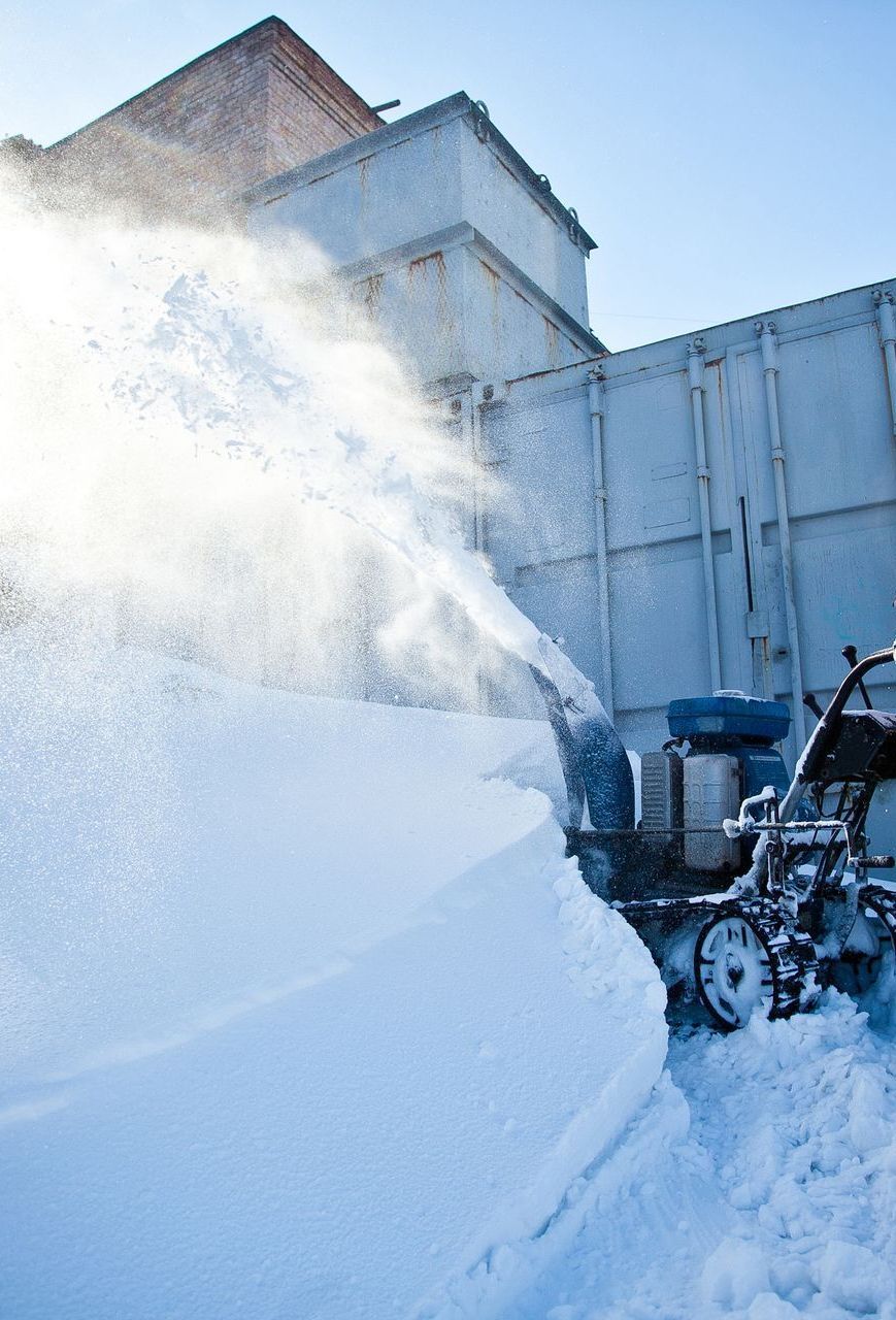 A snow blower is blowing snow from a pile of snow.