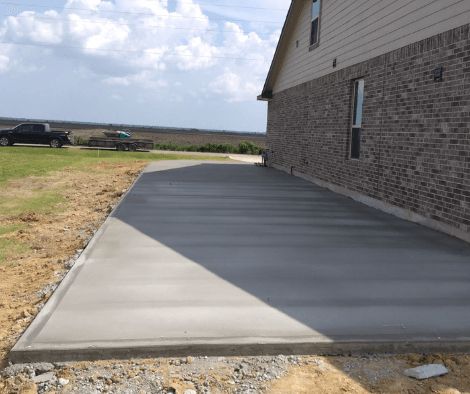 A concrete driveway is being built in front of a brick house.