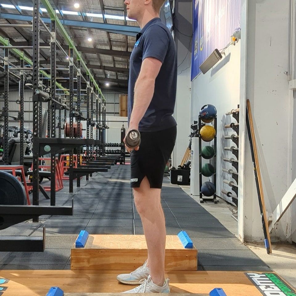Individual Confidently Holding a Dumbbell in a Gym Setting — Return to Performance Physiotherapy in Epsom, VIC