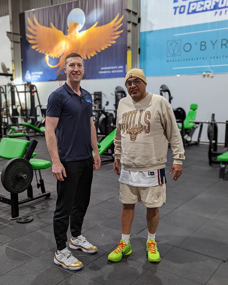 Two Men Are Standing Next to Each Other in a Gym — Return to Performance Physiotherapy in Epsom, VIC