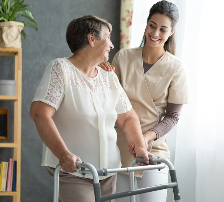 A Woman is Helping an Older Woman Use a Walker — Return to Performance Physiotherapy in Epsom, VIC