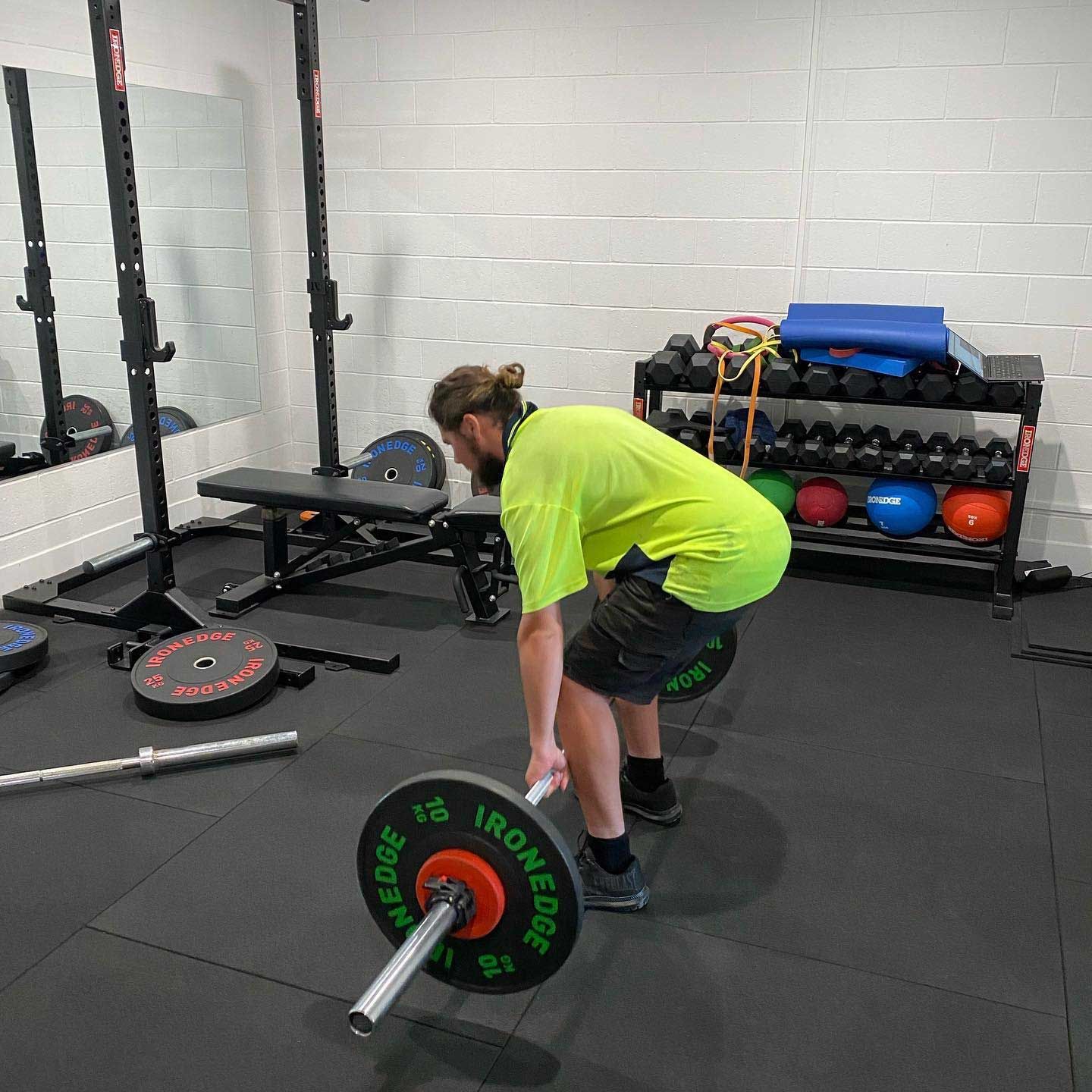 A Man Lifts a Barbell in a Gym, Showcasing Strength And Fitness — Return to Performance Physiotherapy in Epsom, VIC