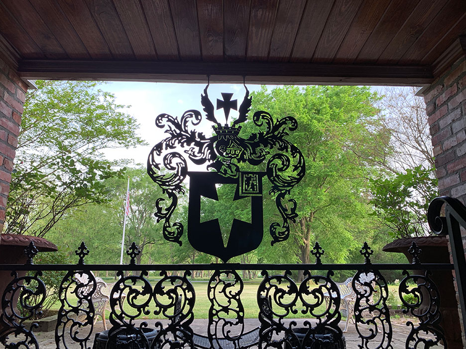 Decorative wrought-iron crest overlooking a green park from a covered balcony
