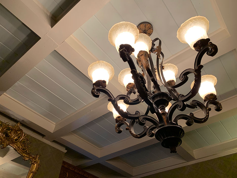 Ceiling chandelier with lit frosted shades against a coffered white ceiling