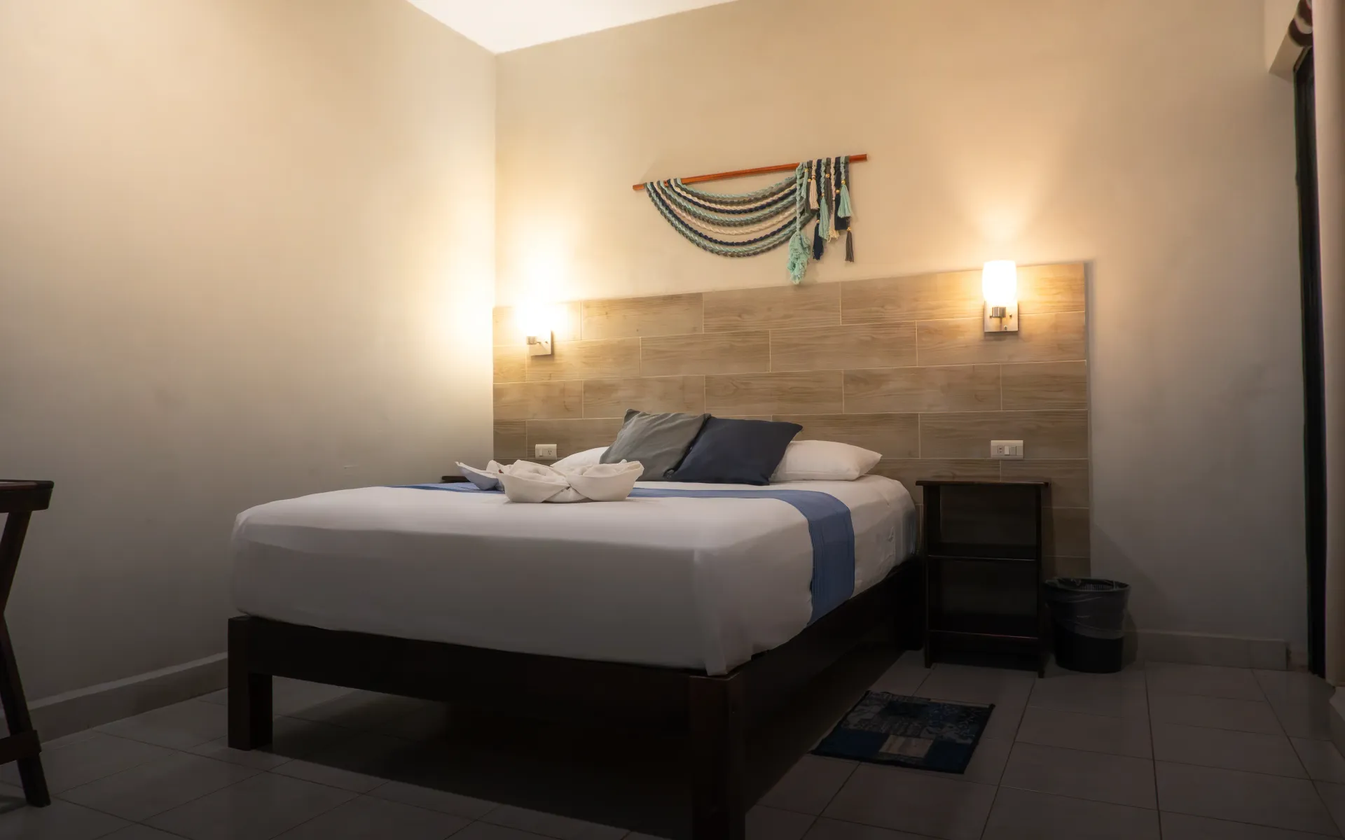 Habitación acogedora con una cama bien hecha, luces de pared cálidas y un adorno de pared.