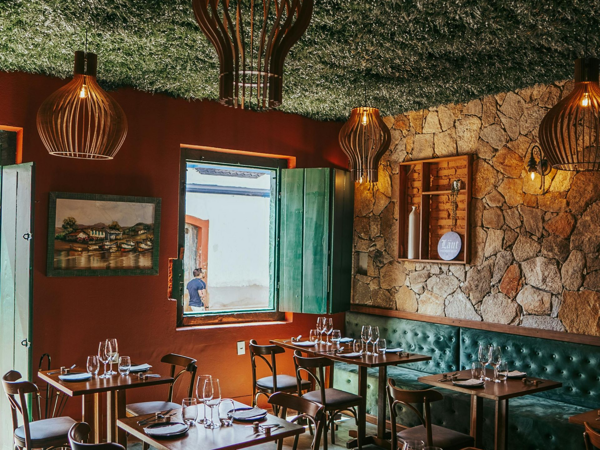 Interior acogedor de una cafetería con cabinas de color turquesa, mesas de madera, lámparas colgantes.