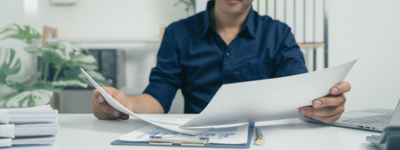 A man is sitting at a desk holding a piece of paper.
