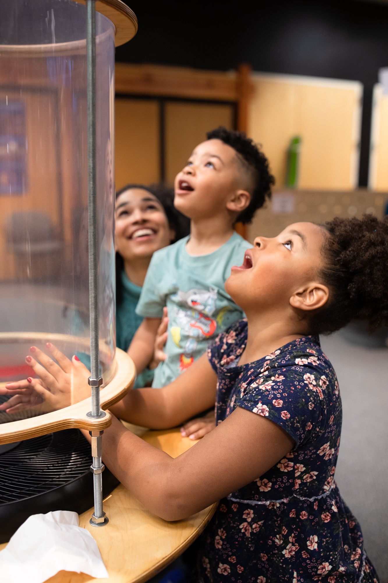 Two children and a mother look on excitedly at the wind tunnels as part of ScienceWorks' Take Flight exhibit