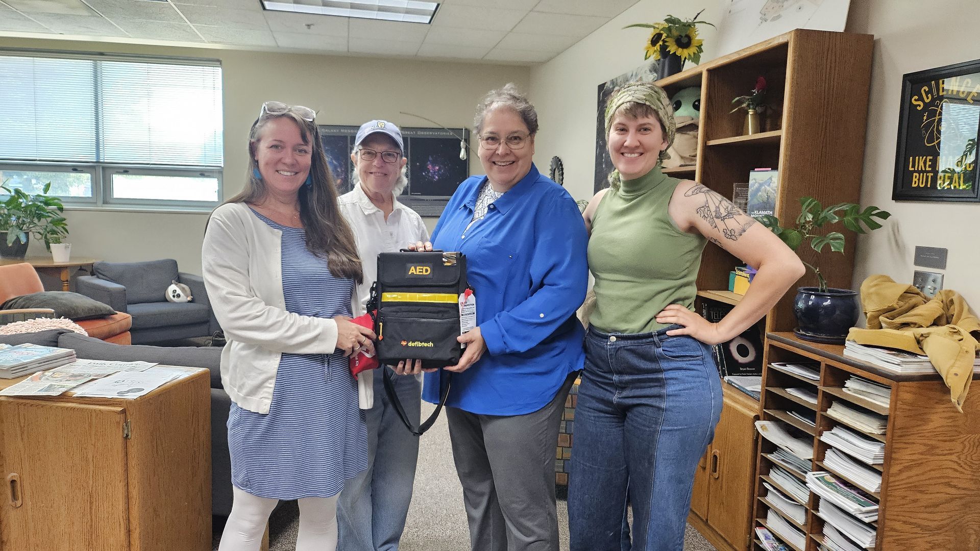 ScienceWorks staff holding our new Automated External Defibrillator (AED). From left to right: Cassie Preskenis (Operations Manager), Diane (Educator), Dr. Gabriela Chavarria (Executive Director), Liz Koonce ( Exhibits & Facilities Coordinator).