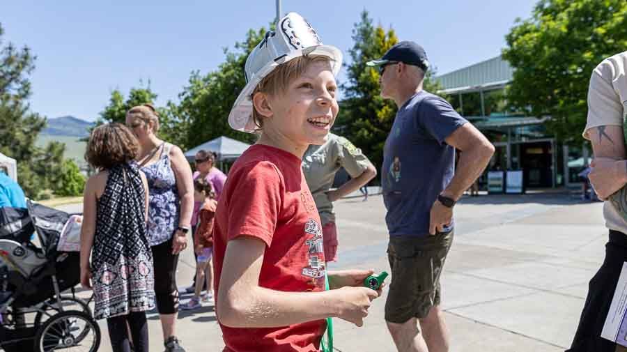 Young boy in a plastic fire fighting helmet standing on the plaza in front of ScienceWorks at Sparking Action!