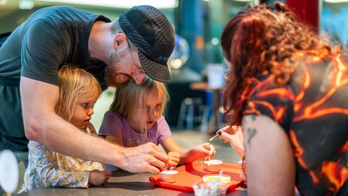 Two children and an adult being led  in a facilitated activity by ScienceWorks staff person