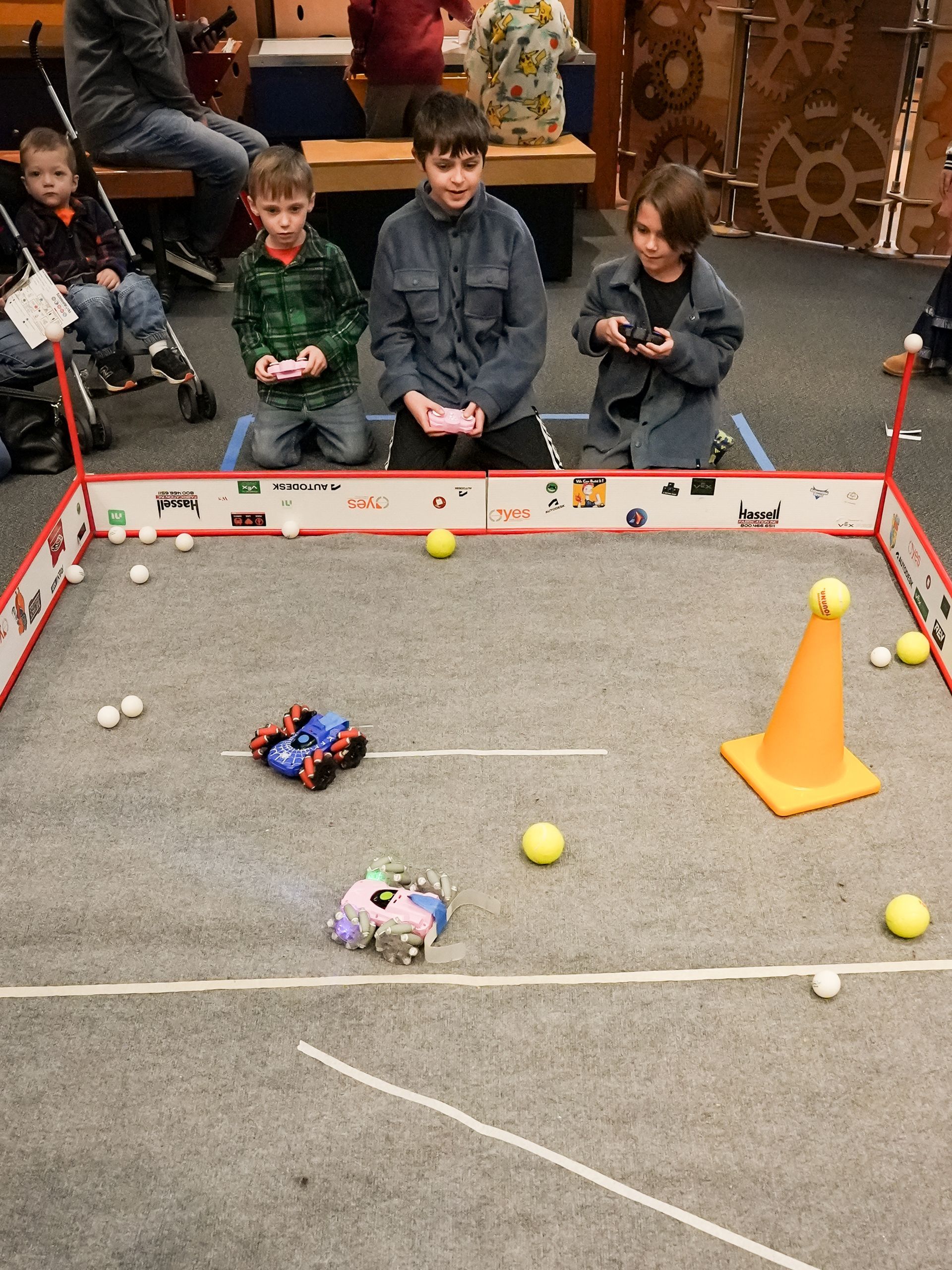Children controlling small robots  at ScienceWorks, with balls and a cone.