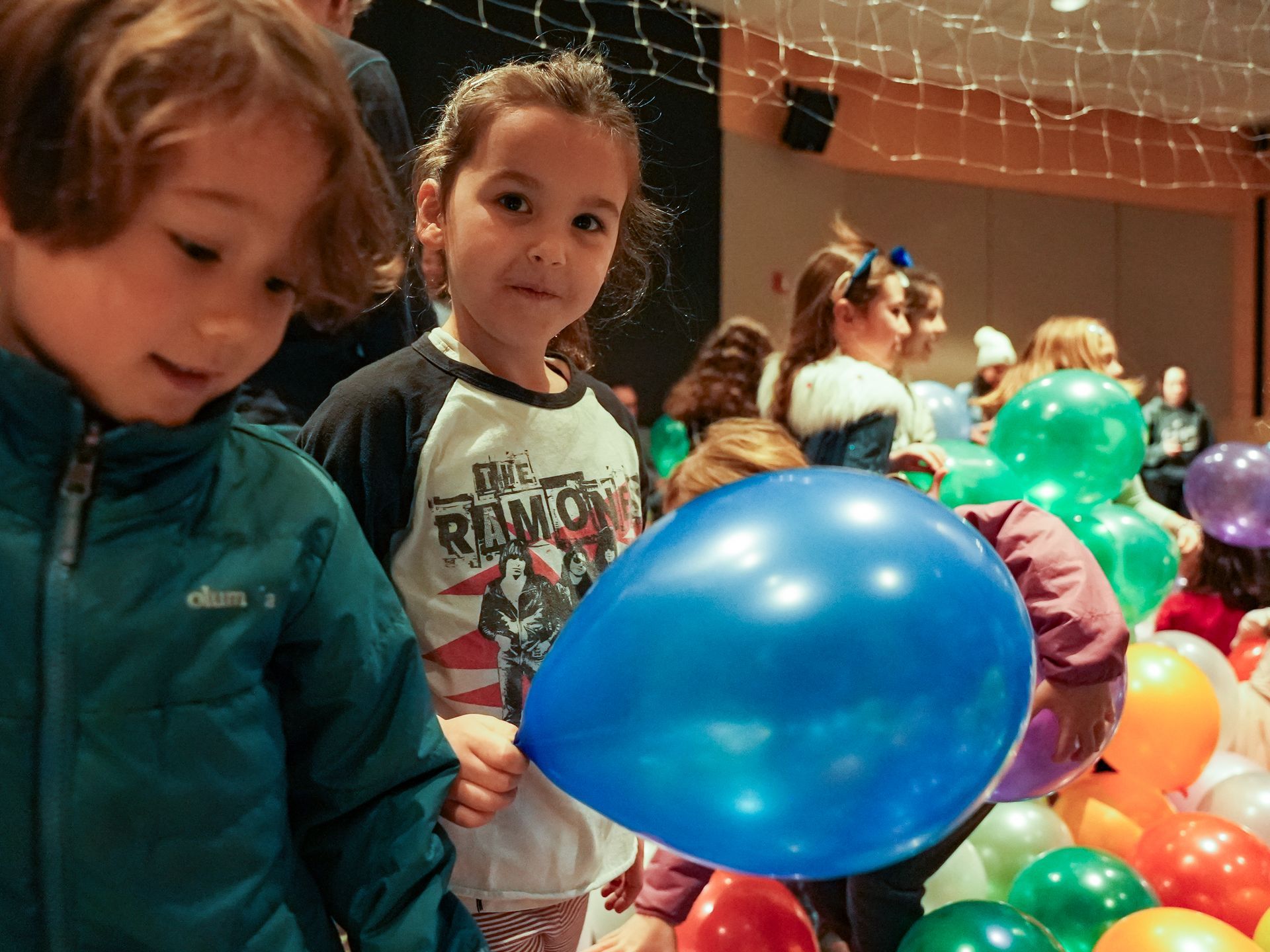 Children holding a blue balloon at an event with many colorful balloons in a room at ScienceWorks.