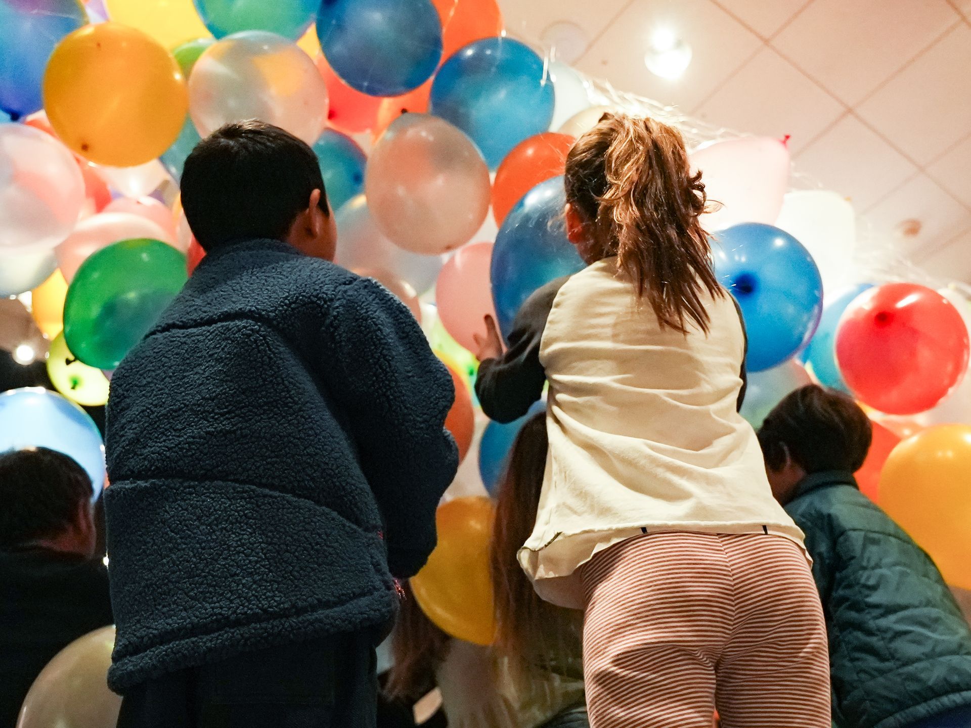Children reaching towards colorful balloons at ScienceWorks.