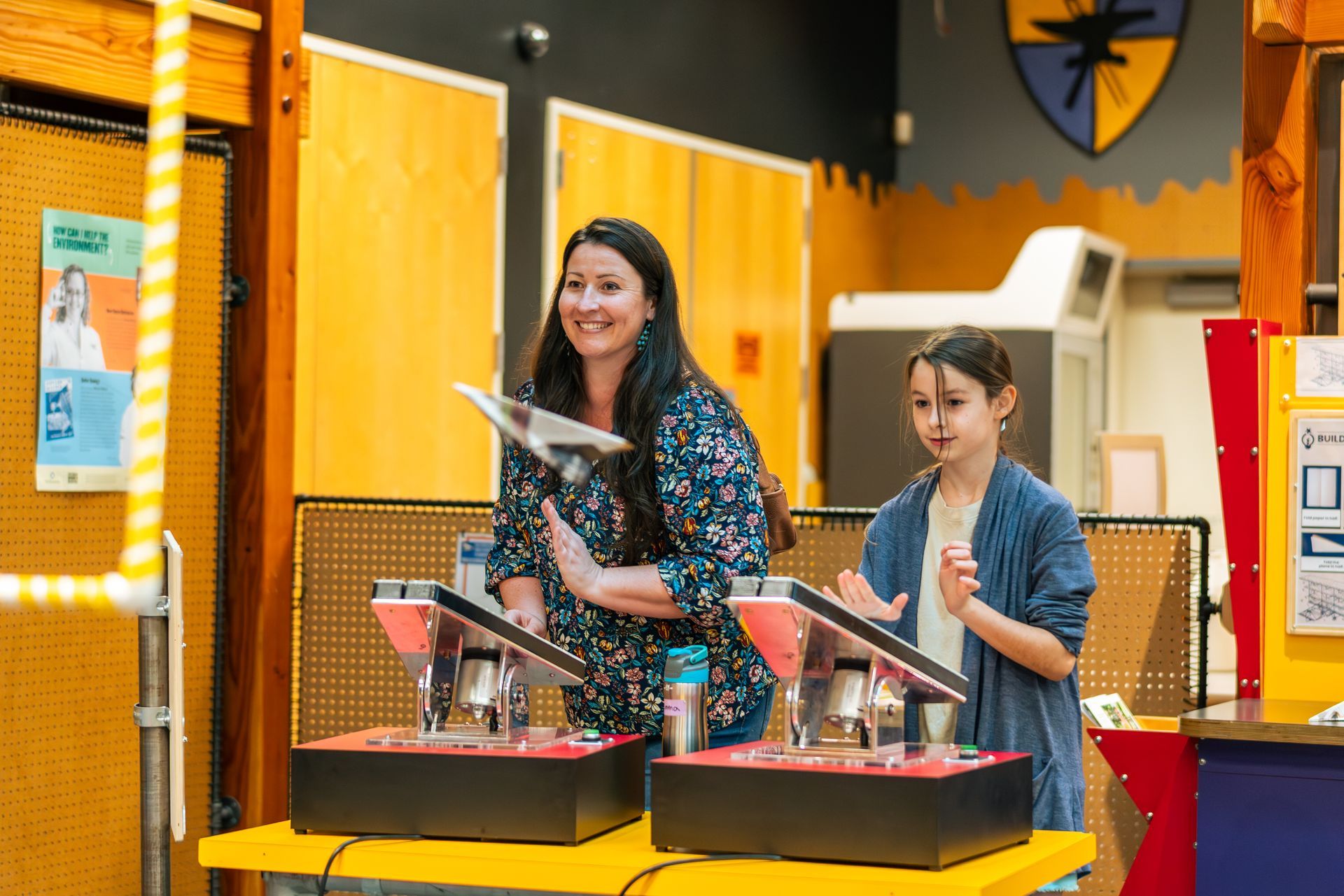 An adult and child using the Wing Zingers exhibit to launch paper airplanes