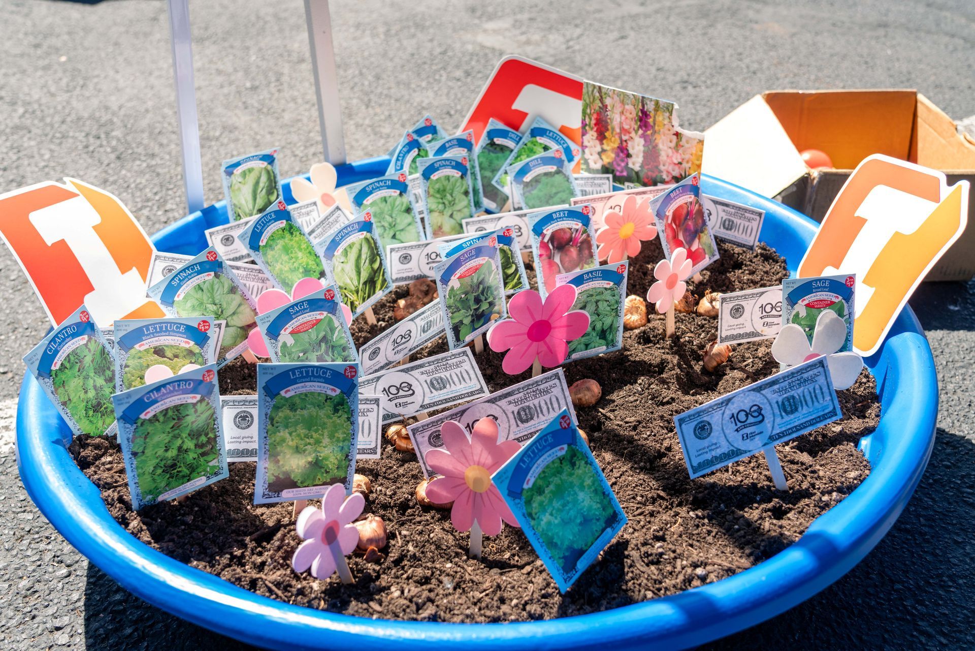 Blue bowl of soil with colorful handmade plant markers and paper flowers outdoors