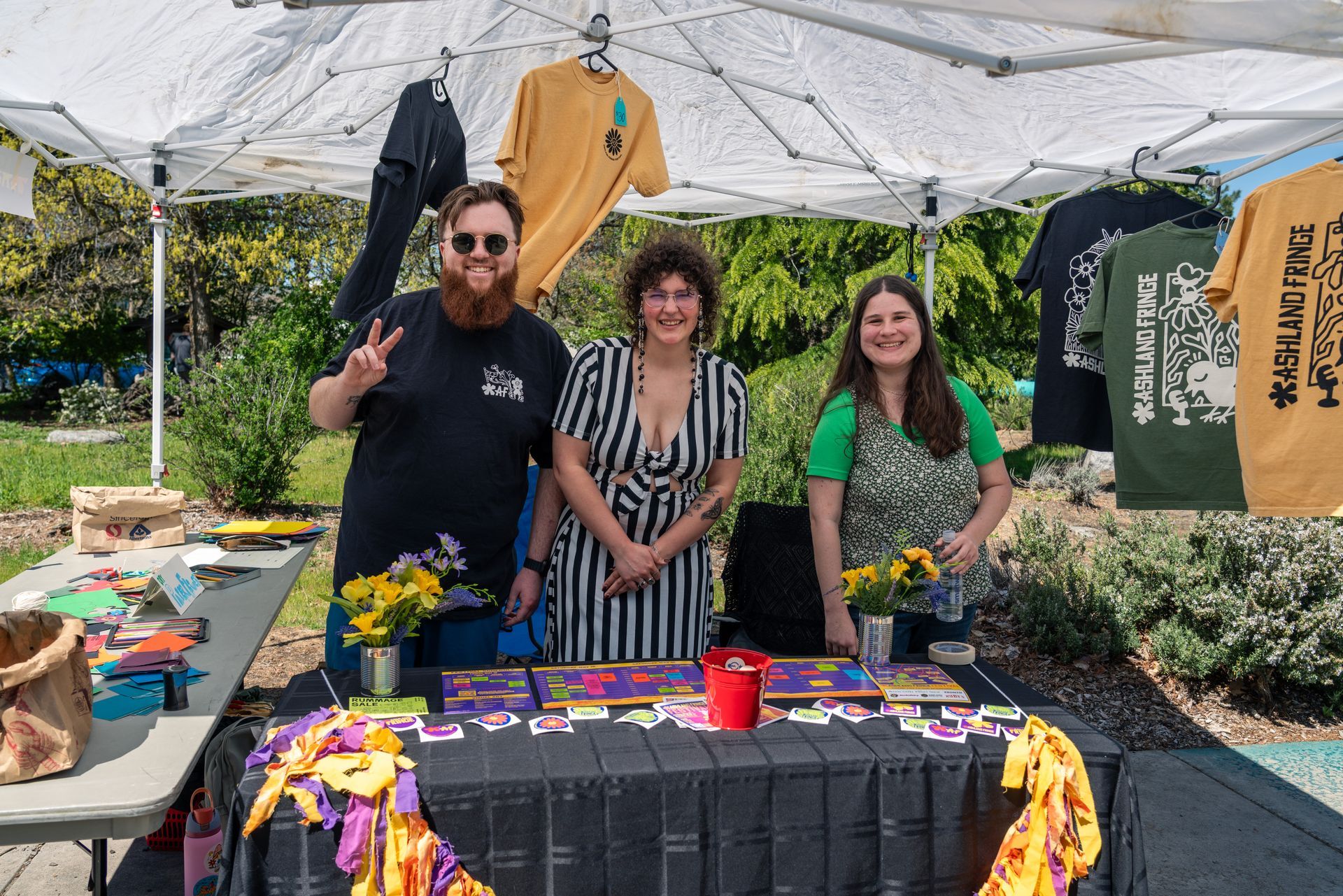 People at a community outreach booth under a white tent, with children gathered around tables of materials.