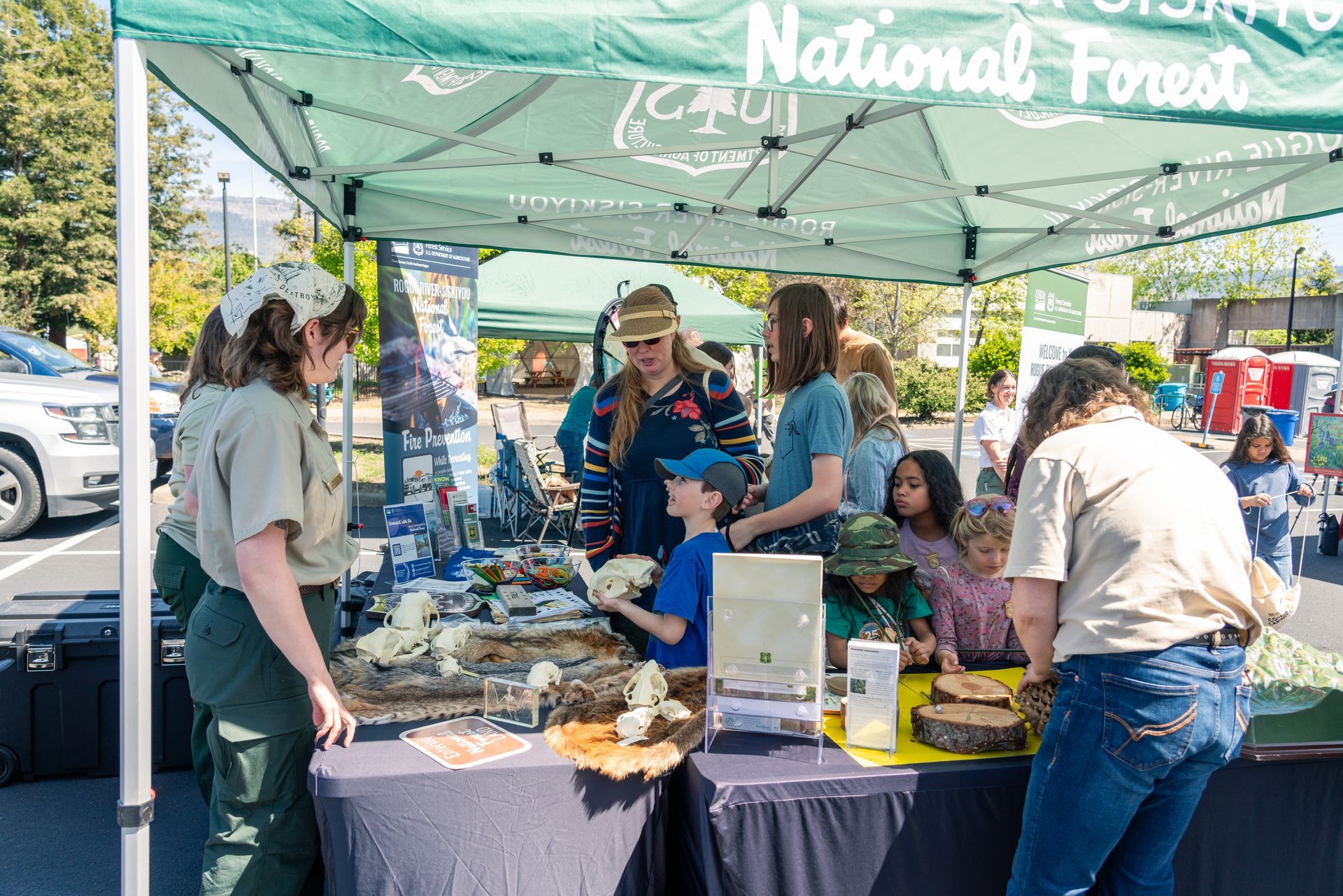 People browsing a National Forest booth under a green canopy at the earth day celebration at scieneworks
