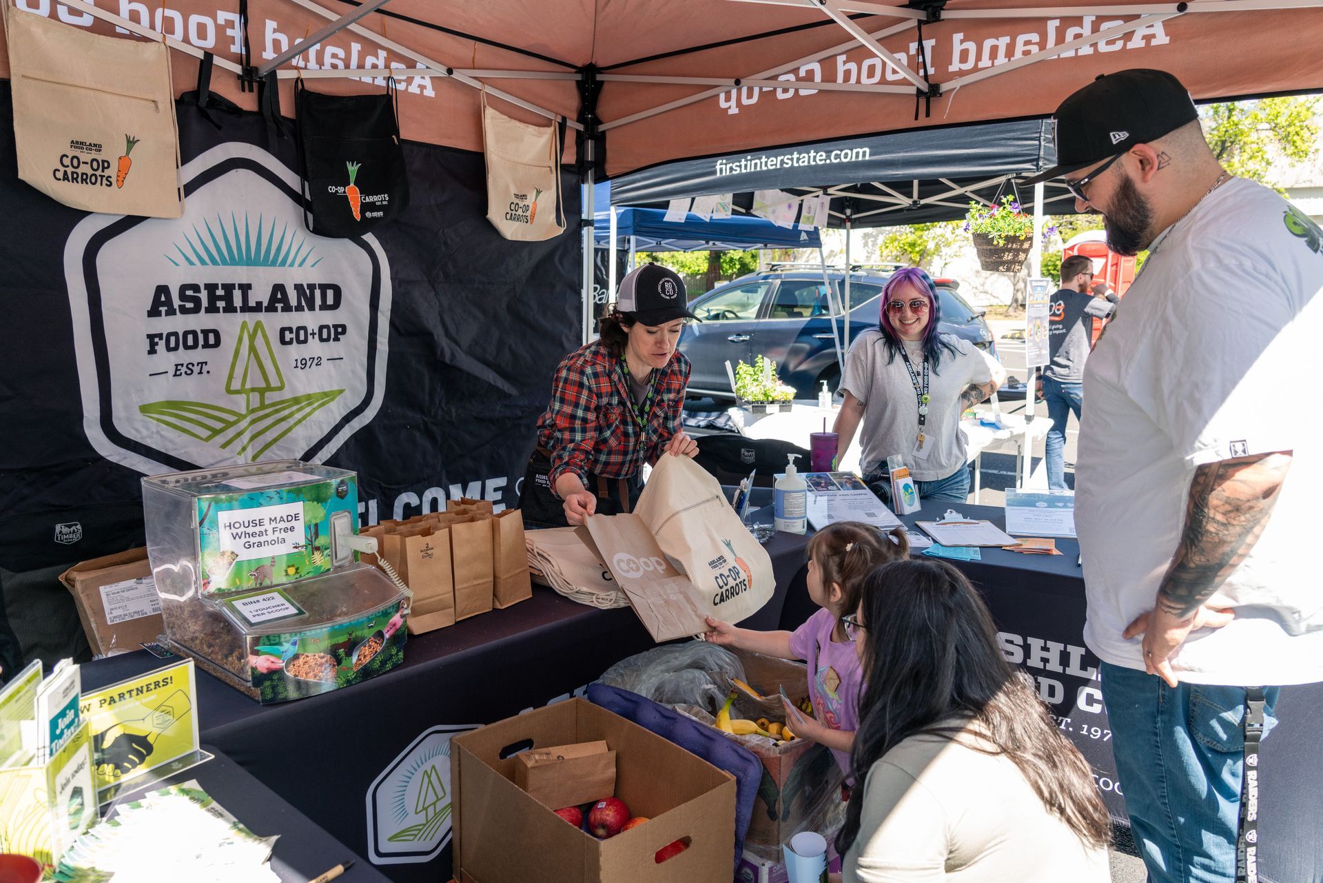 People chatting at an Ashland Food Co-op booth under a tent at the earth day celebration at scienceworks