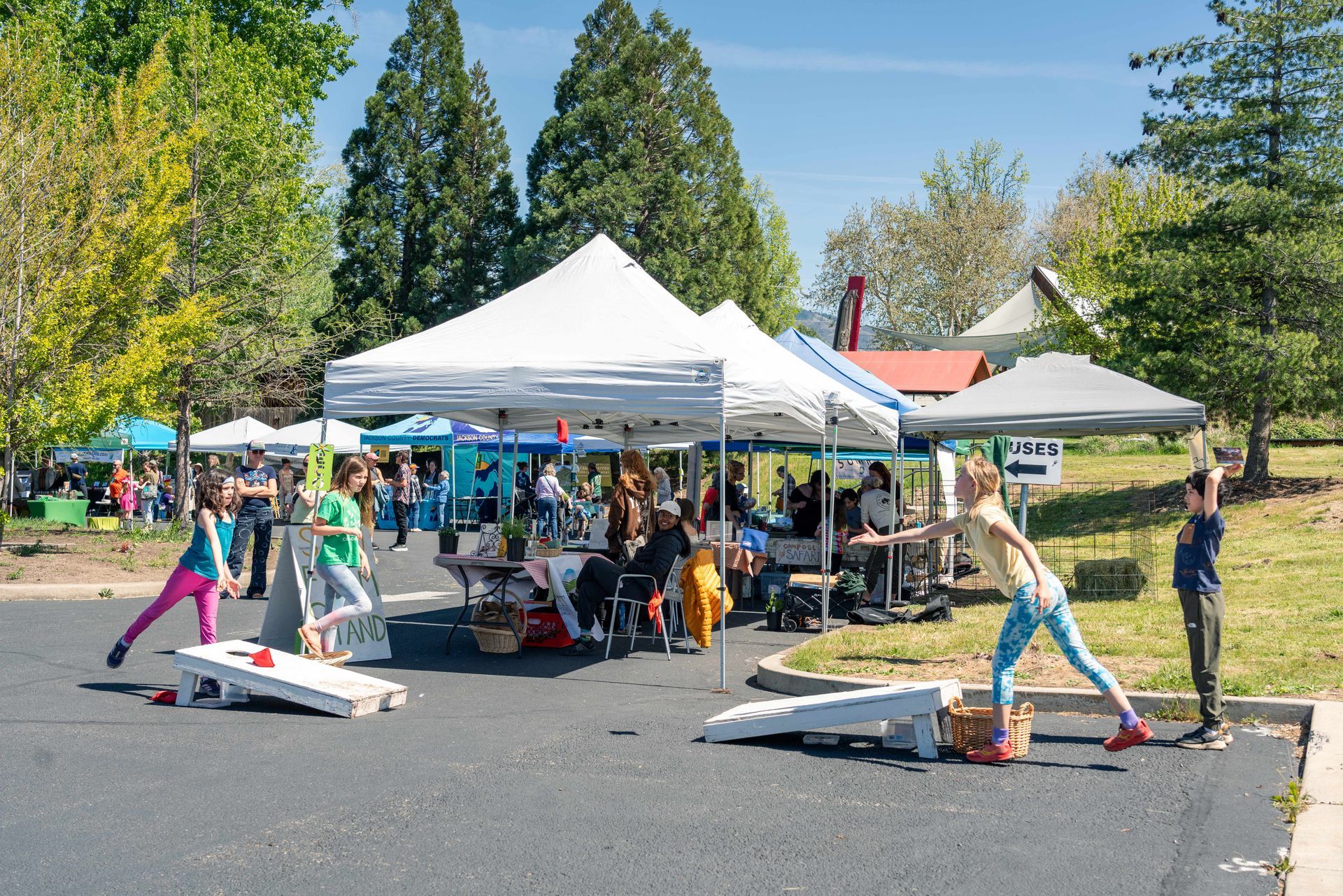 People at a community outreach booth under a white tent, with children gathered around tables of materials.